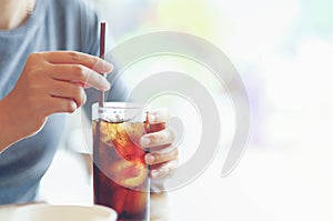 closeup woman Hand holding glass of cola drink in restaurant background, Woman hand glass soft drinks with ice