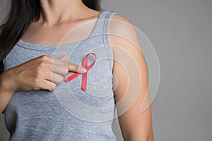 Closeup woman hand holding red ribbon HIV, world AIDS day awareness ribbon. Healthcare and medicine concept