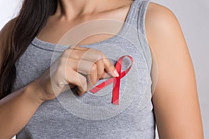 Closeup woman hand holding red ribbon HIV, world AIDS day awareness ribbon. Healthcare and medicine concept