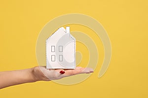 Closeup of woman hand holding small white paper house, concept of dream home purchase, mortgage.