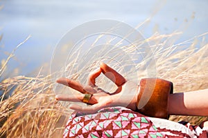 Closeup of woman hand in mudra gesture practice yoga meditation outdoor in grass summer day