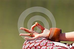 Closeup of woman hand in mudra gesture practice yoga meditation outdoor by the lake summer day