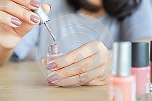 Closeup woman hand painting nail with vanish photo