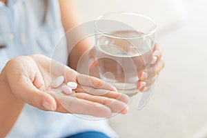 Closeup woman hand with pills medicine tablets and glass