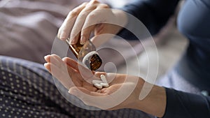 Closeup of woman hand pouring capsules from a pill bottle into hand