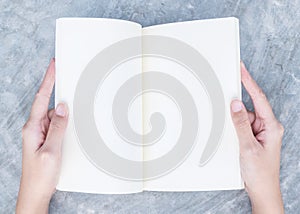 Closeup woman hand read a book in her free time on concrete desk in top view textured background under day light in the garden