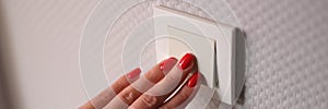 Closeup of woman hand is turned off on light switch at home