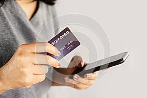 Closeup woman hand using smart phone and credit card paying from home