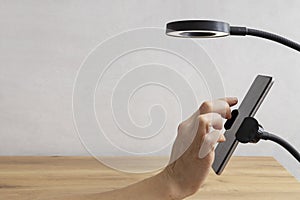 Closeup of woman hand who using her phone to record vlog video, vlogger lamp on the wooden table.Empty space