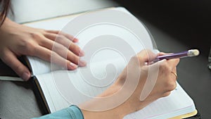 Closeup woman hand writing on notebook on table, girl work with book or diary at home