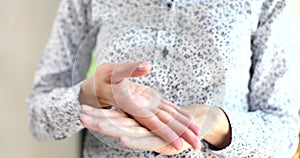 Closeup of woman hands applying white moisturizer to skin