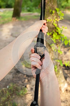 Closeup of woman hands attach the hammock straps on the tree.