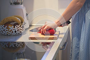 Closeup of woman hands cut red pepper in kitchen