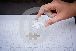 Closeup of woman hands fulfill the last piece of jigsaw puzzle t