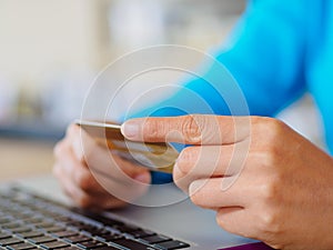 Closeup woman hands holding a credit card and using laptop