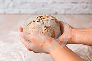 Closeup woman hands holding kneaded dough from rye flour over marble countertop in bright kitchen. process of baking health bread