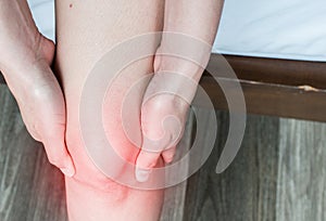 Closeup of woman hands holding and massage her knee, suffering from knee pain.