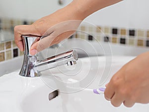 Closeup woman hands is holding toothbrush with toothpaste in sink bathroom