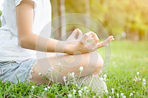 Closeup of woman hands meditating in yoga pose or lotus position on green grass,asian child girl practicing yoga meditation in