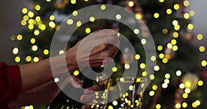 Closeup of woman hands opening bottle of champagne on background of Christmas . Woman hands open bottle of sparkling