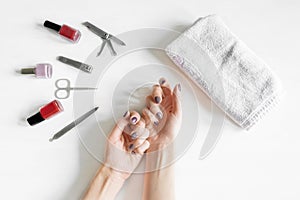 Closeup of woman hands with polished nails and manicure instruments, bottles of nail polish. caucasian woman receiving