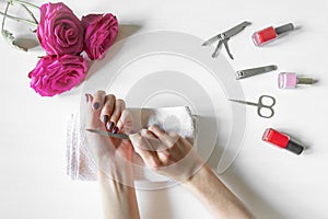 Closeup of woman hands with polished nails and manicure instruments, bottles of nail polish. caucasian woman receiving