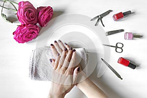 Closeup of woman hands with polished nails and manicure instruments, bottles of nail polish. receiving french manicure