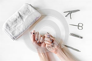 Closeup of woman hands with polished nails and manicure instruments. caucasian woman receiving french manicure at home