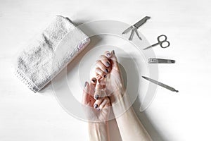 Closeup of woman hands with polished nails and manicure instruments. caucasian woman receiving french manicure at home