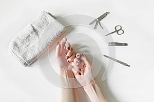 Closeup of woman hands with polished nails and manicure instruments. Young caucasian woman receiving french manicure at