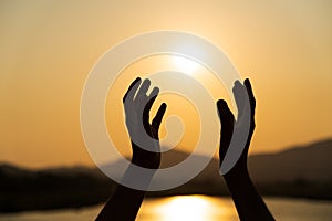 Closeup woman hands praying for blessing from god during sunset background. Hope concept