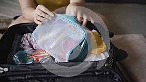 Closeup woman hands put lipstick inside mesh cosmetic bag and put them in luggage. Packing to go on a getaway vacation