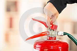 Closeup woman hands with red nailpolish showing how to operate fire extinguisher