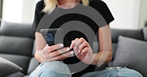 Closeup of woman hands typing on phone sending text message online on social networks on home sofa