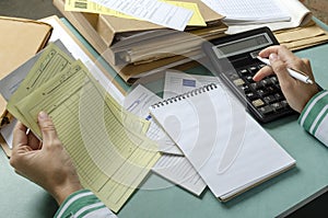 Closeup of woman hands who holding bills and calculating total costs.Office desk and lot of paper, documents, folders on it