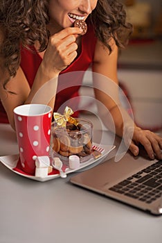 Closeup on woman having christmas cookies and usign laptop