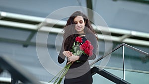 Closeup woman holding flowers at street. Woman smelling red roses outdoors