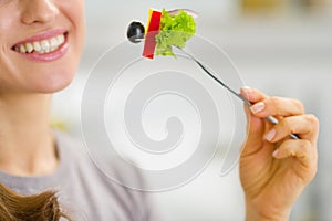 Closeup on woman holding fork with salad