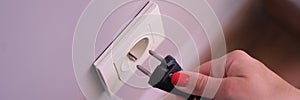 Closeup of woman holding in hand inserts plug into socket