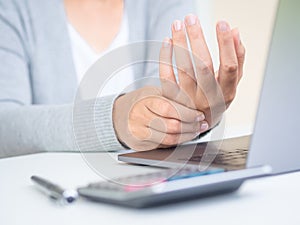 Closeup woman holding her hand pain from using computer long tim