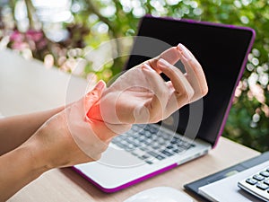 Closeup woman holding her wrist pain from using computer.