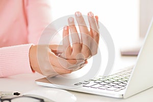 Closeup woman holding her wrist pain from using computer.