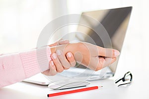 Closeup woman holding her wrist pain from using computer