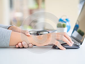 Closeup woman holding her wrist pain from using computer long ti