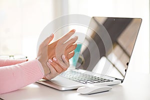 Closeup woman holding her wrist pain from using computer. Office