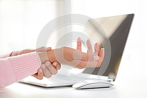 Closeup woman holding her wrist pain from using computer. Office