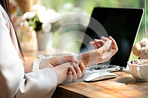 Closeup woman holding her wrist pain from using computer. Office syndrome hand pain by occupational disease