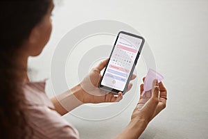 Closeup of woman holding phone and menstrual cup