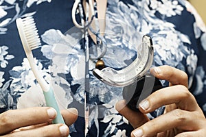 Closeup woman holding teeth whitening kit and brush.