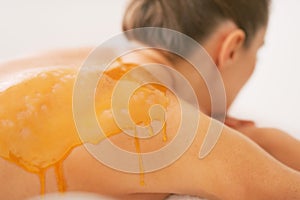 Closeup on woman with honey on back laying on massage table